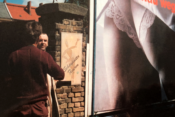 Darsteller und Maskenbildner vor einem Plakat