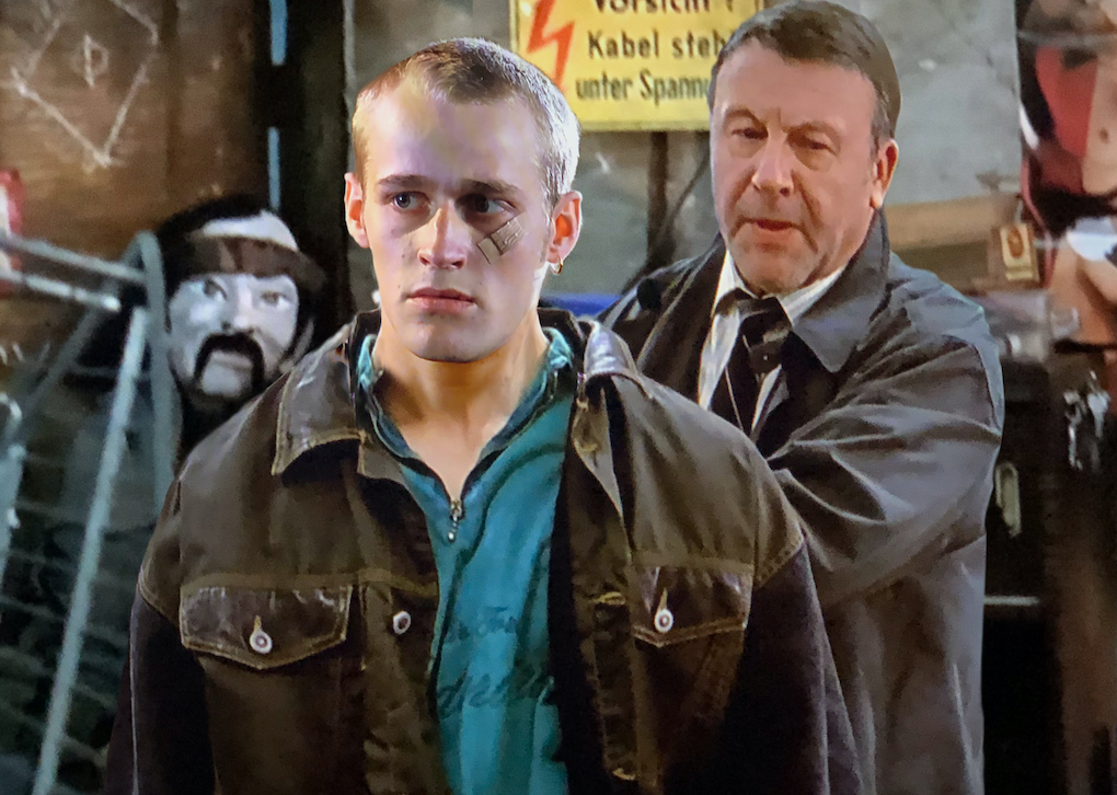 Alex zieht eine Waffe